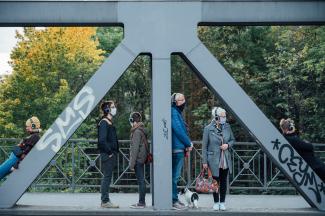 Personen mit Kopfhörern stehen auf einer Brücke.