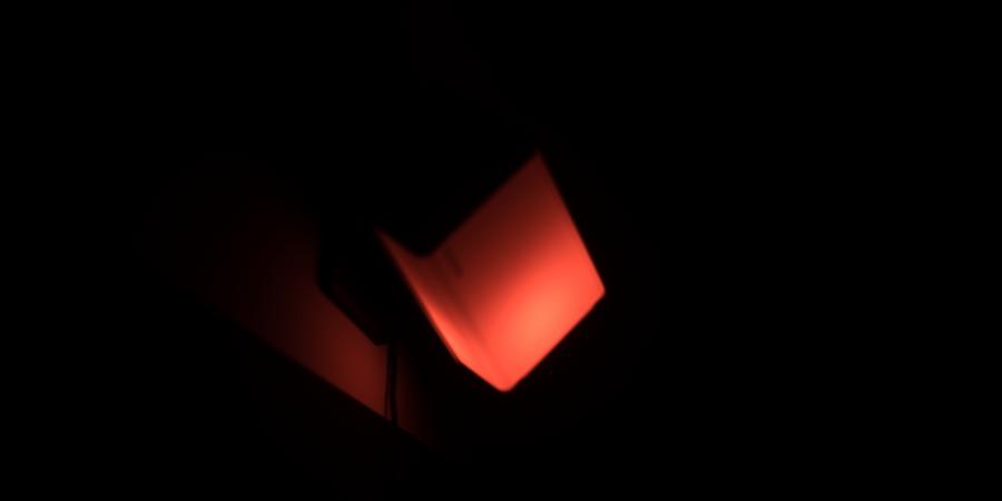 Eine rote eckige Lichtform steht in einem dunklen Raum 